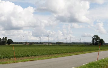 En väg med vindkraftverk i bakgrunden En väg med vindkraftverk i bakgrunden