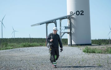 En man i hjälm i en vindkraftspark En man i hjälm i en vindkraftspark