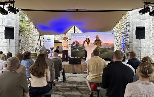 Publik och deltagare vid ett seminarium i Almedalen, framför en scen med texten “Electricity is hope”.