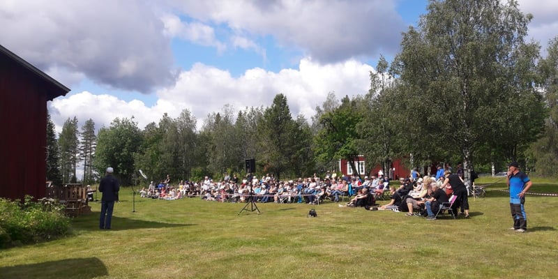 Besökare på Baksjölidendagen lyssnar på en presentation utomhus i solsken Besökare på Baksjölidendagen lyssnar på en presentation utomhus i solsken