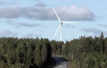 En skogsväg med ett vindkraftverk i bakgrunden En skogsväg med ett vindkraftverk i bakgrunden